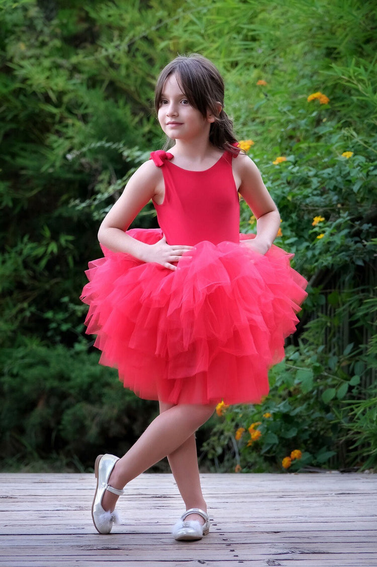 a little girl in a red dress posing for a picture